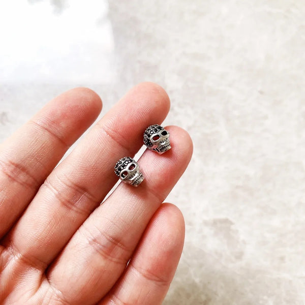 Paire de boucles d'oreilles tête de mort montrée dans la main