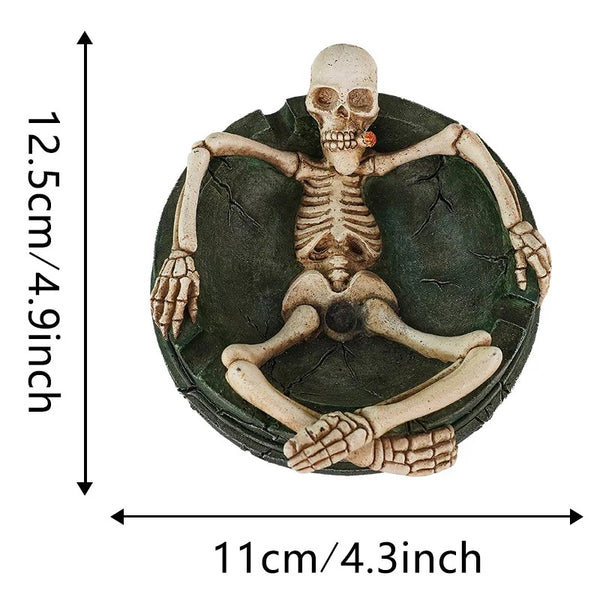 Cendrier tête de mort en résine avec squelette assis, dimensions indiquées de 11 × 12,5 cm