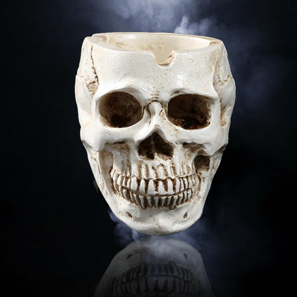 Cendrier tête de mort en résine blanche vieillie, crâne aux orbites sombres et récipient creusé sur le dessus